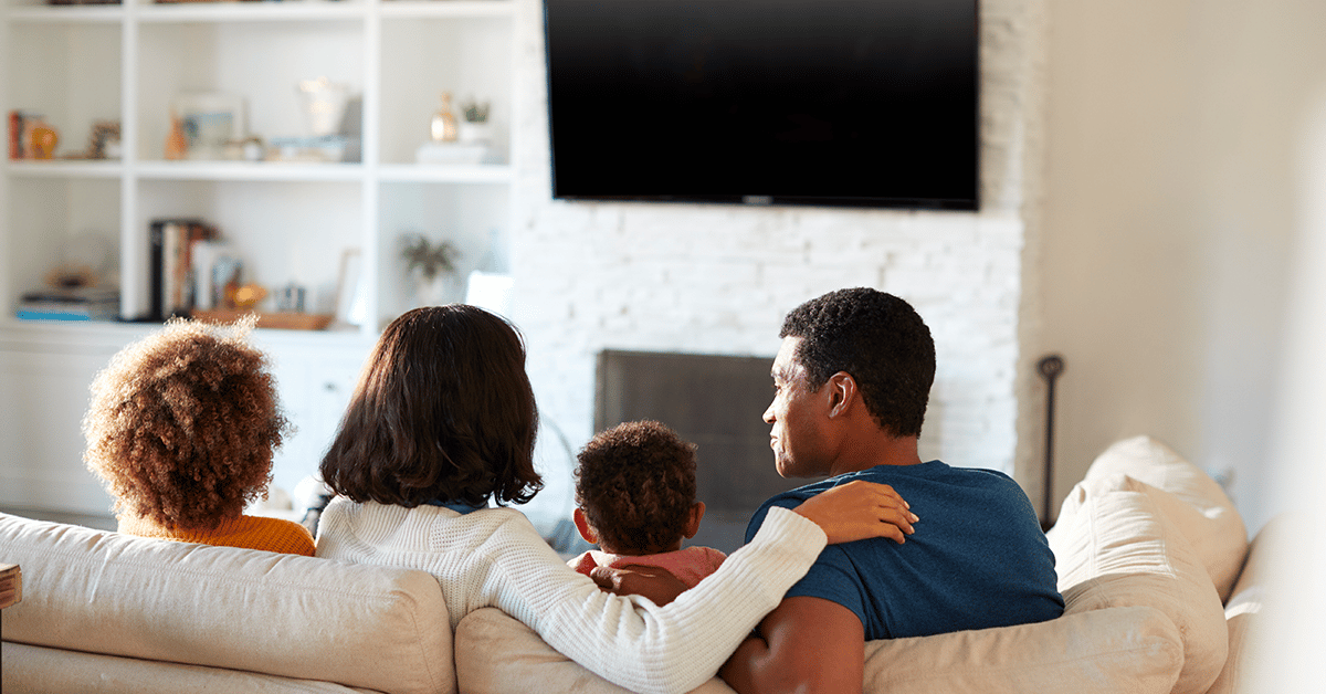A family of four sitting together in living room