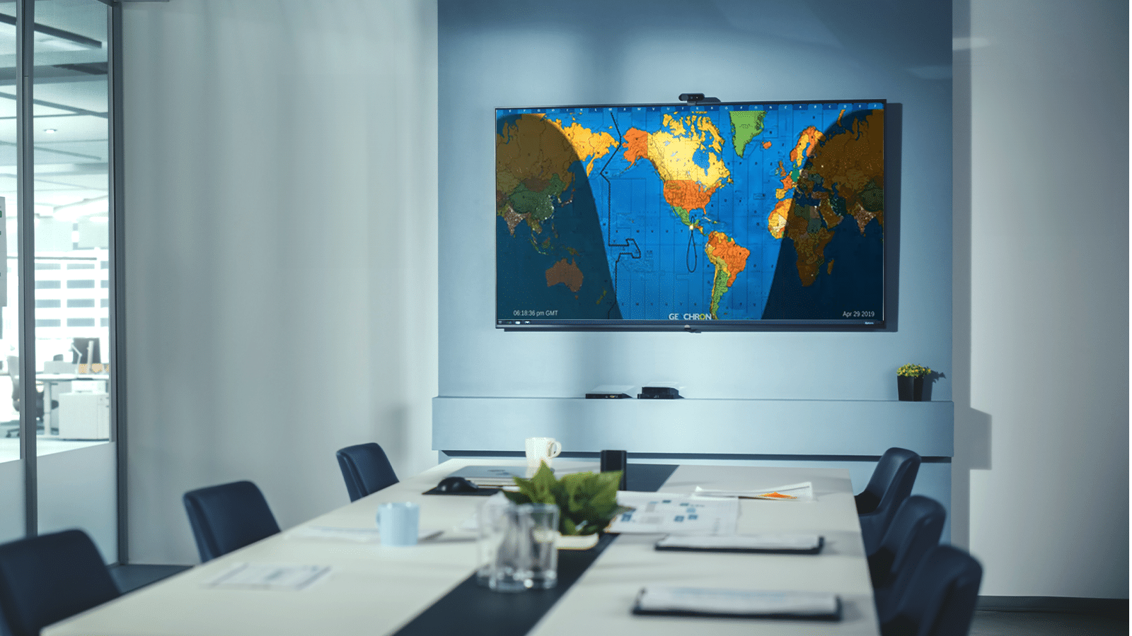 Modern conference room with a large screen displaying a world map, papers, and laptops on a long table, featuring Azulle Mini PCs, and a city view outside the window.