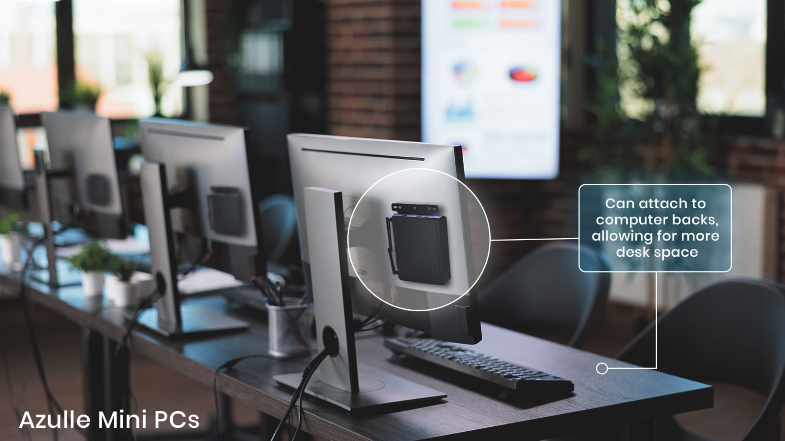 A row of computer monitors on desks in a bustling office environment, each fitted with an attached mini PC on the back for saving desk space. Text label states, "Thin Client Replacement: Can attach to computer backs, allowing for more desk space." Ideal for large businesses seeking efficiency.