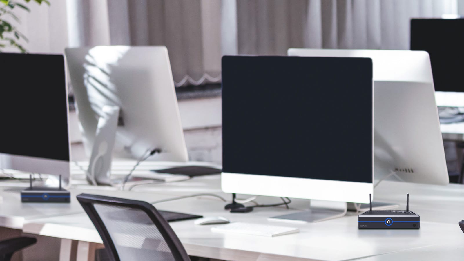 Empty office workspace with multiple desktop computers and a mini PC on the desk, ideal for large businesses looking to implement Mini PCs as a thin client replacement.
